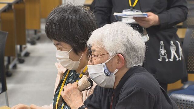 補聴器に音声を届けるマイクを使って、朋子さんに状況を伝える通訳介助員